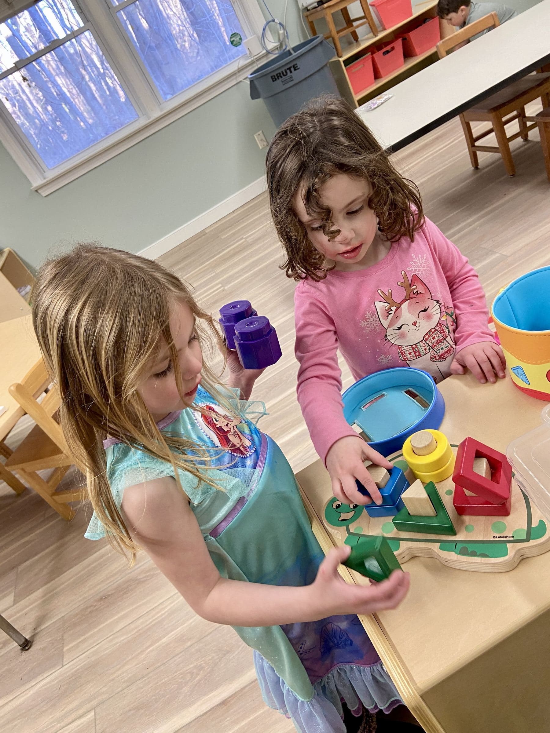 Two little girls sorting shapes at a low table during Parents' Night Out
