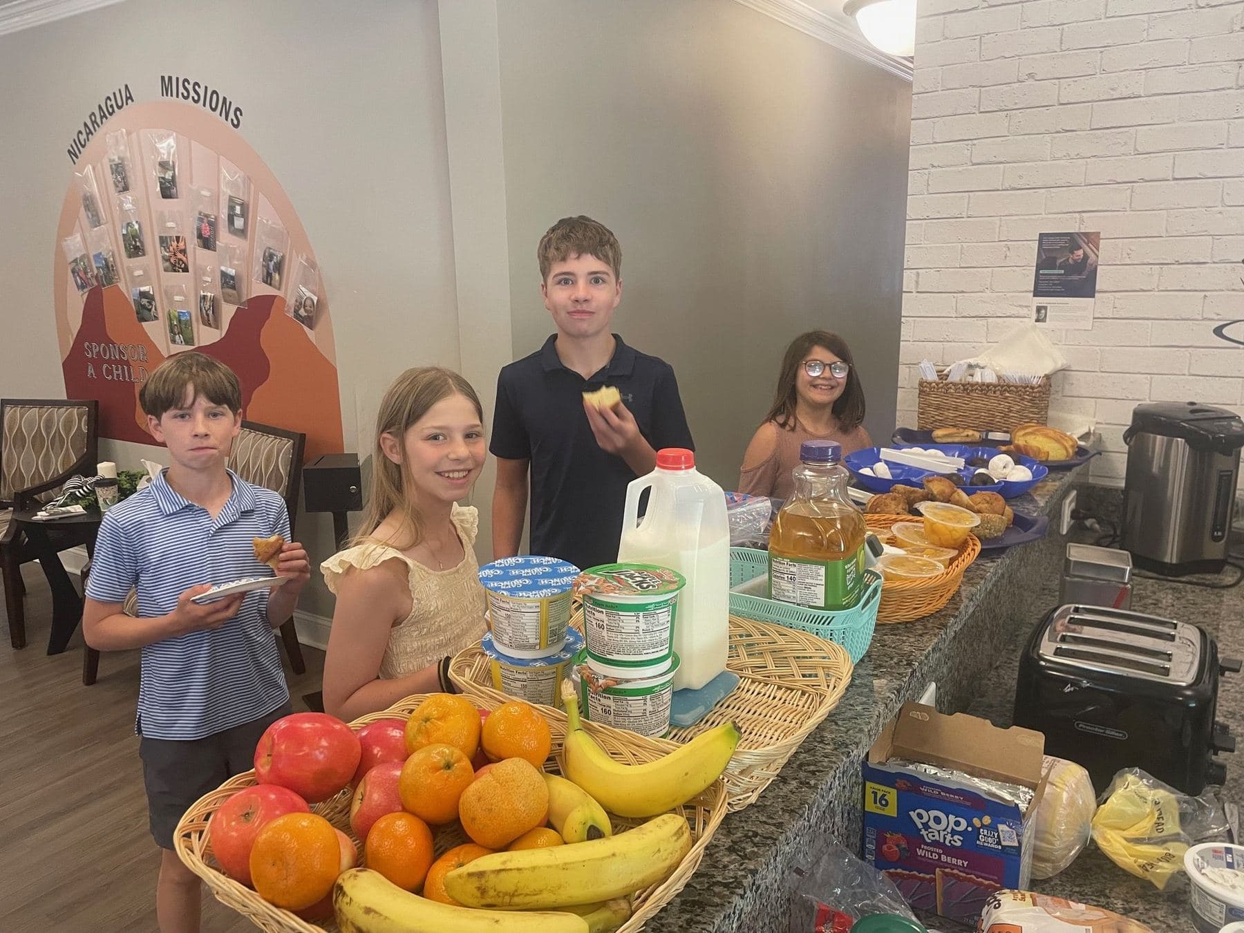 Preteens getting breakfast at the counter, in front of the wall map tracking the church's Nicaragua mission partners