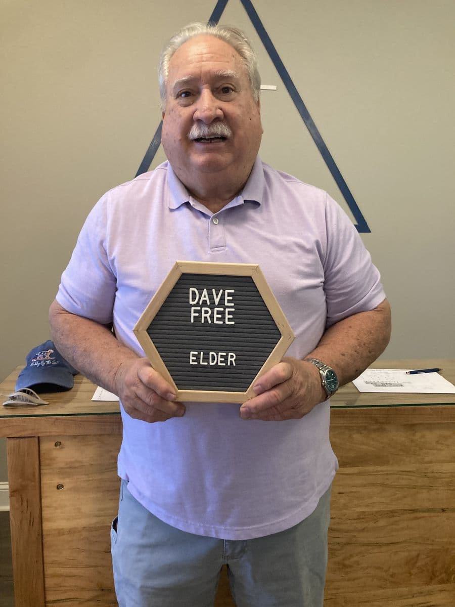 Dave Free holding a letterboard reading Dave Free, Elder