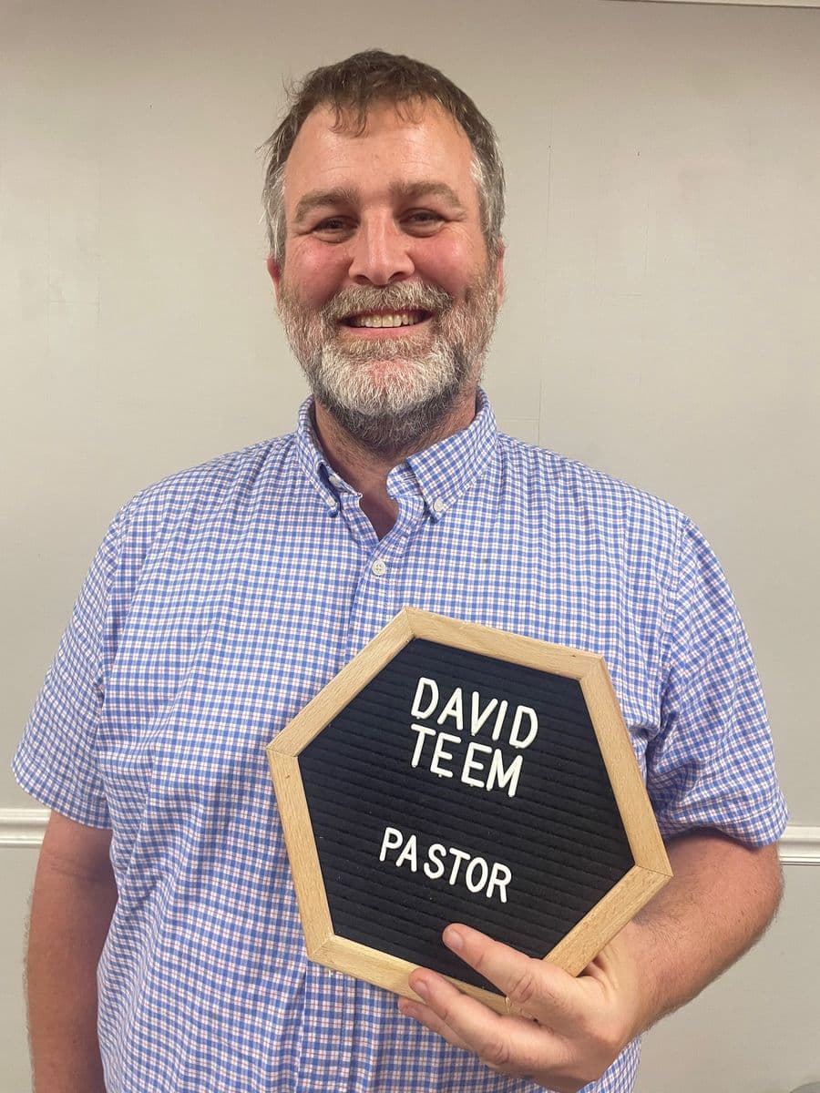 Pastor David Teem holding a letterboard reading David Teem, Pastor