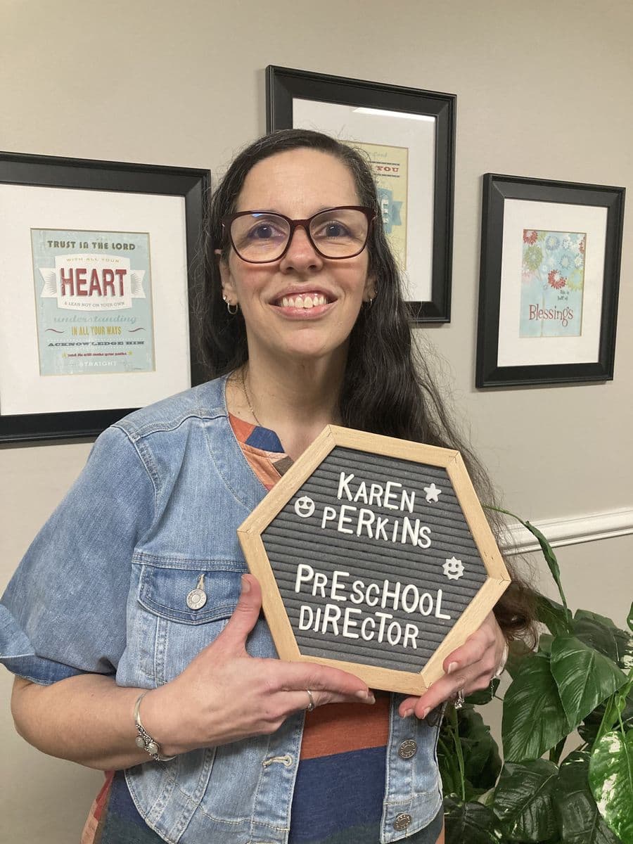 Karen Perkins in the church office holding a letterboard reading Karen Perkins, Preschool Director