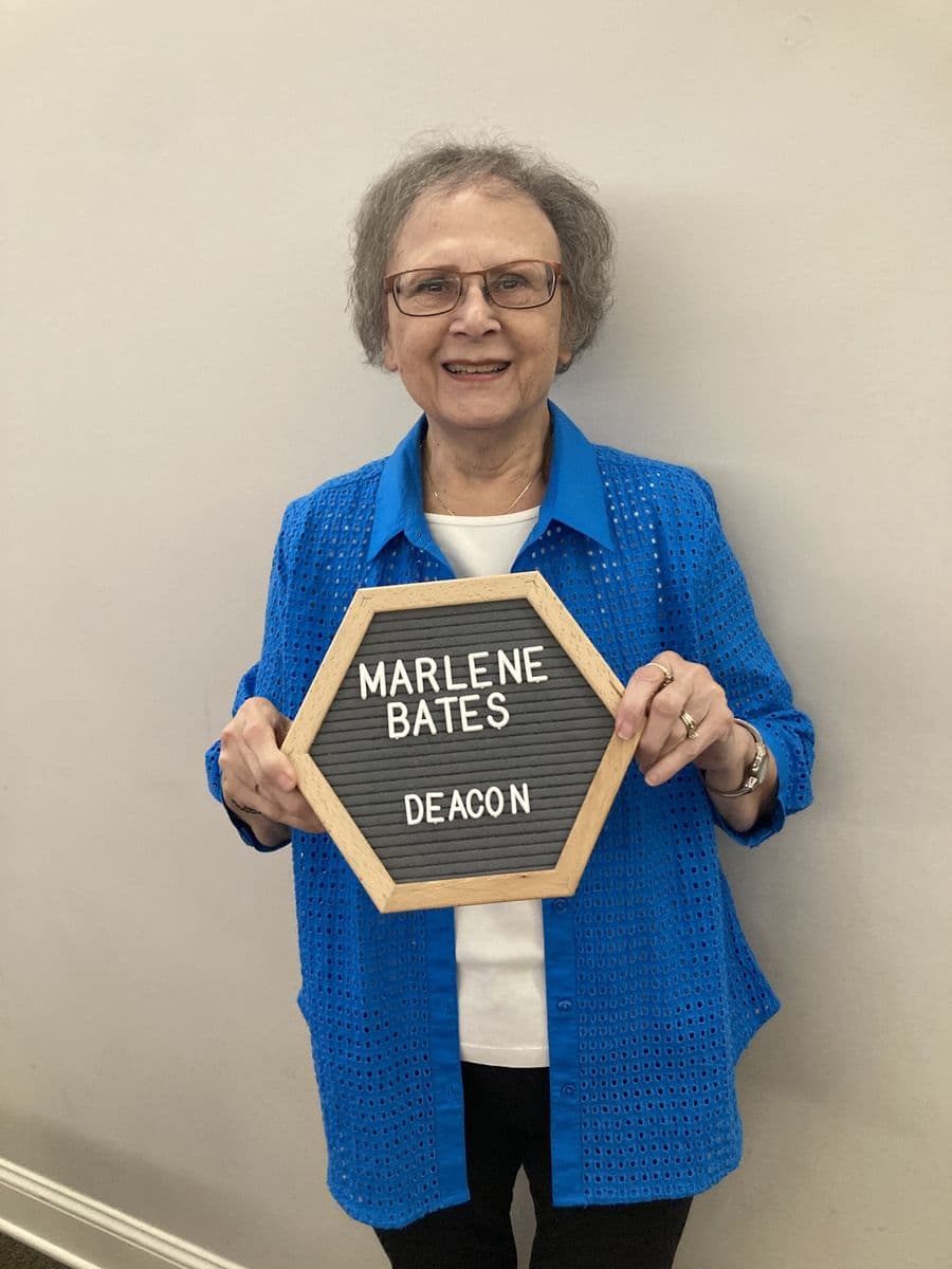 Marlene Bates holding a letterboard reading Marlene Bates, Deacon