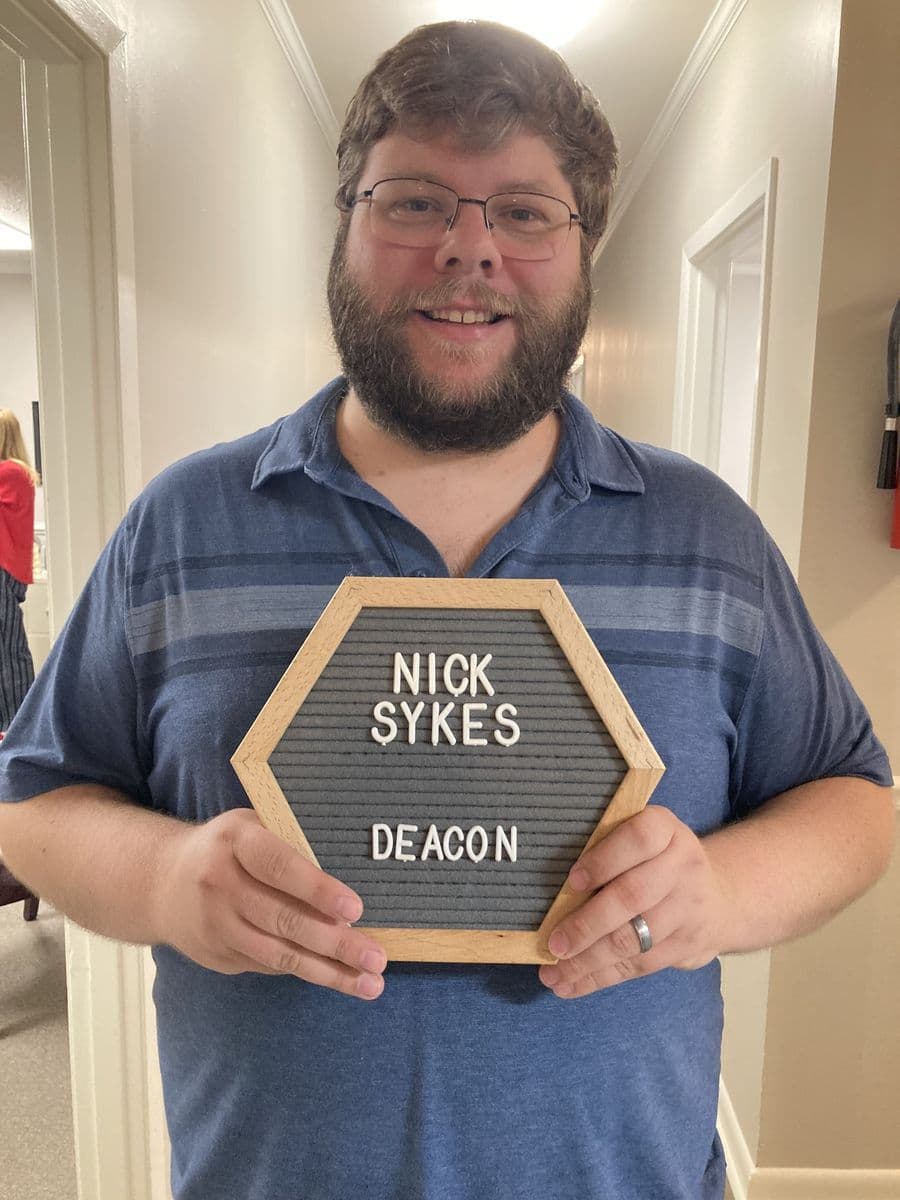 Nick Sykes holding a letterboard reading Nick Sykes, Deacon