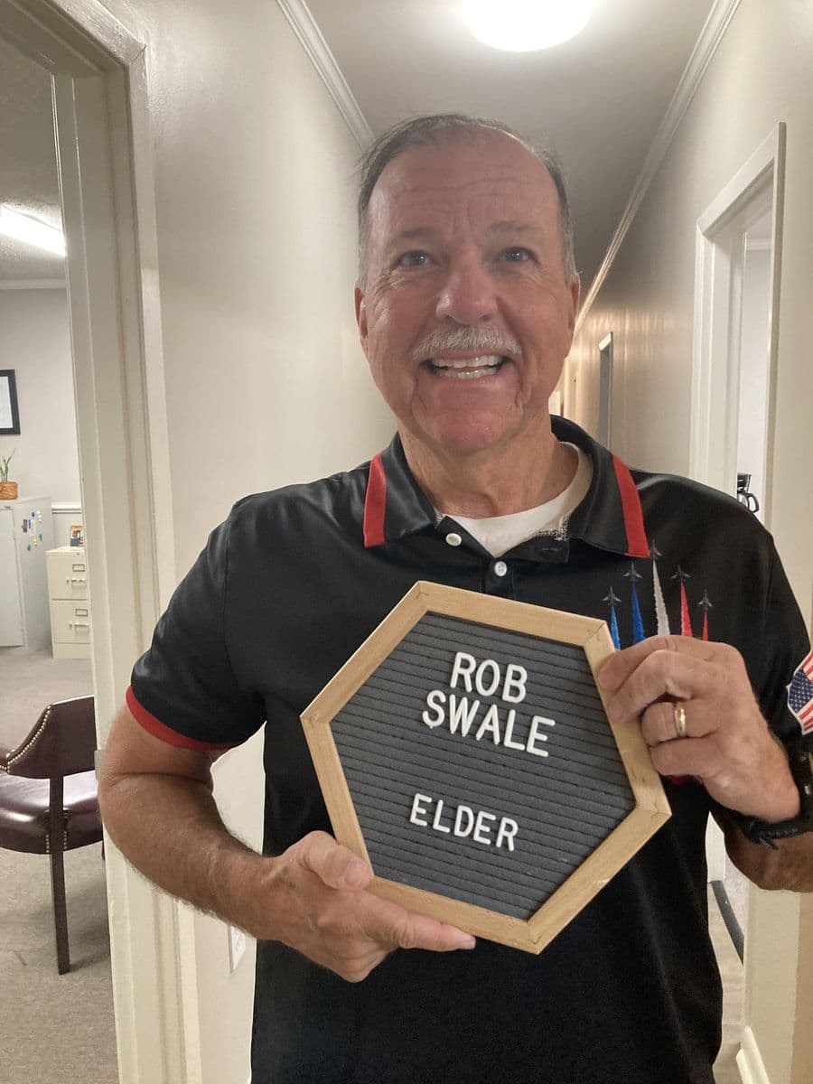 Rob Swale holding a letterboard reading Rob Swale, Elder