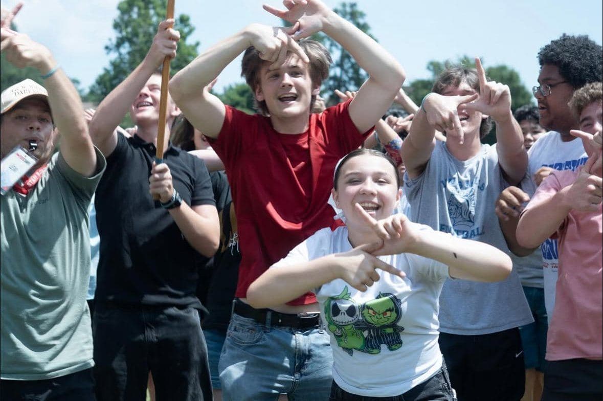 The youth group outside with hands in the air, mid-cheer during an outdoor game